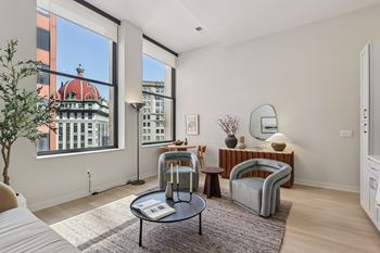 A living room with a large window and a view of a building with a red roof at LiveWell Apartments, Pittsburgh